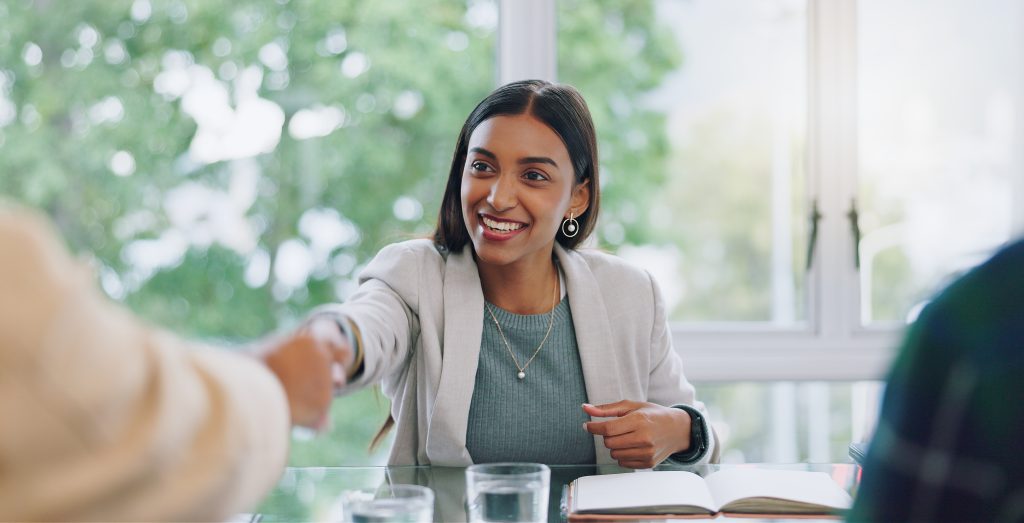 Business woman, handshake and interview thank you with success and agreement in office. Happy, hiring and female professional at company with motivation and shaking hands with job introduction Preventie