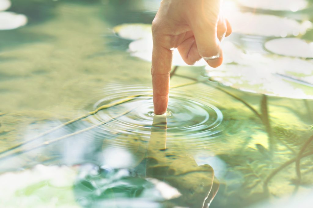 person touches the water with his hand